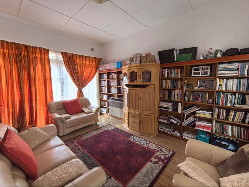 A living room featuring built-in wooden shelving units, laminate flooring, and a tiled ceiling, offering a functional space with ample storage.