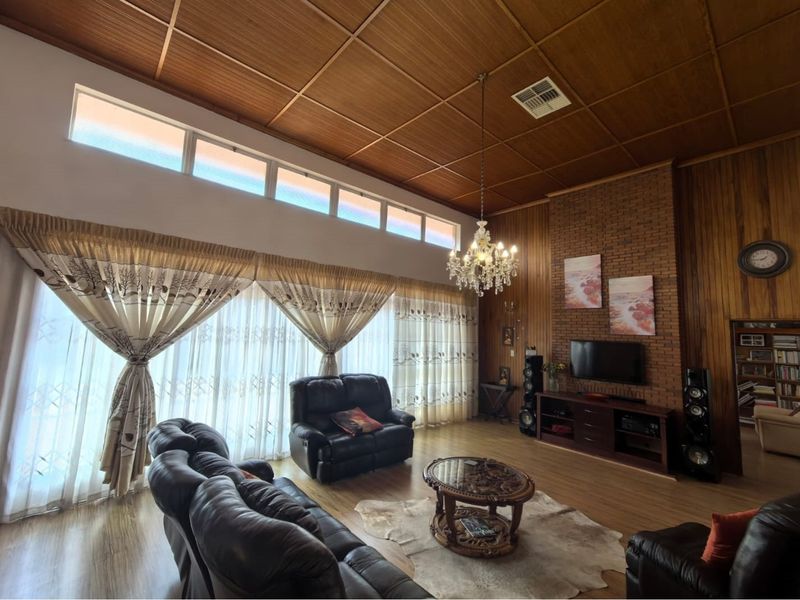 Spacious living room featuring a high timber panelled ceiling, exposed brick feature wall, and large windows with natural light.