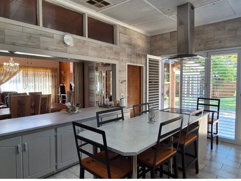 Spacious kitchen featuring a central island, modern extractor fan, tiled flooring, and large sliding doors providing direct access to the garden.