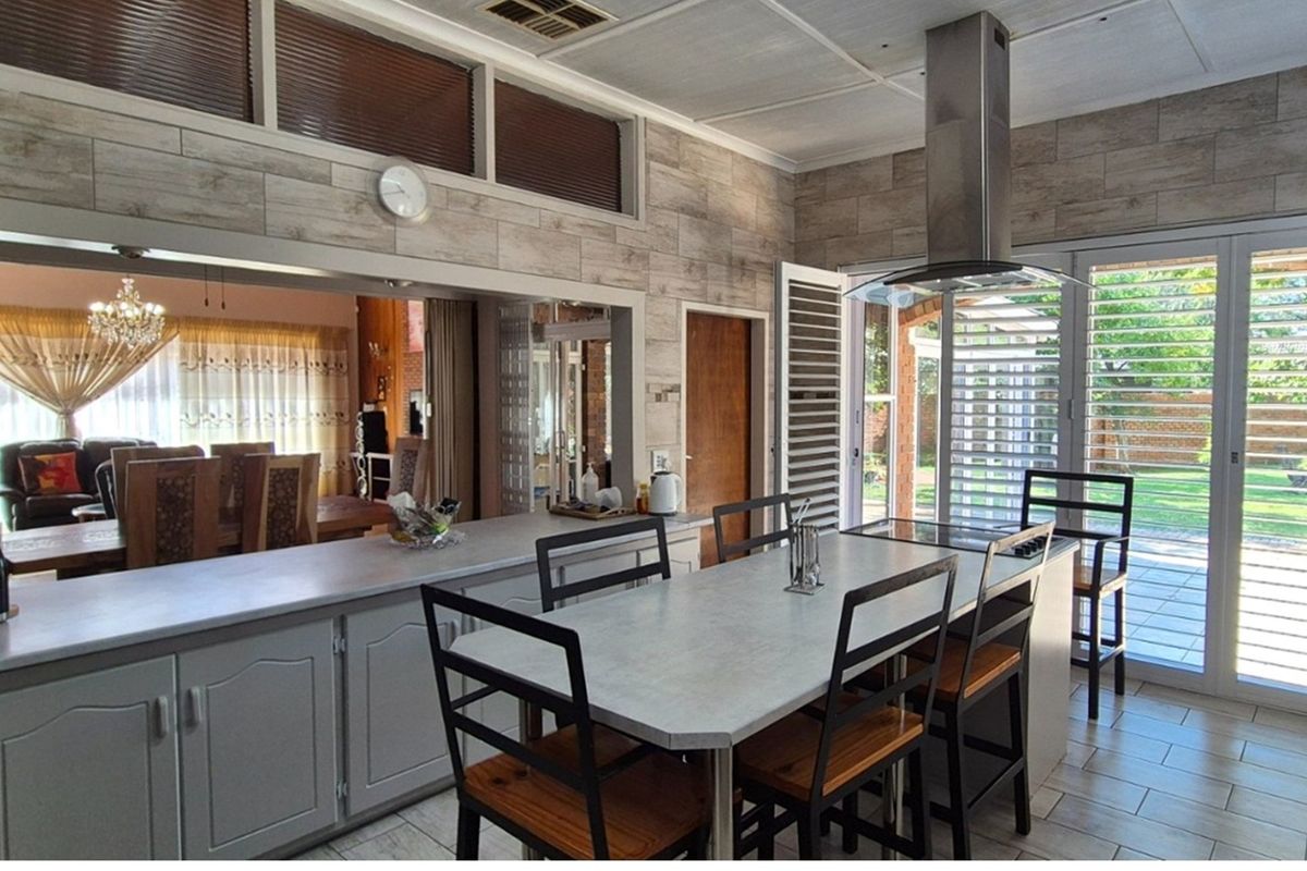Spacious kitchen featuring a central island, modern extractor fan, tiled flooring, and large sliding doors providing direct access to the garden.