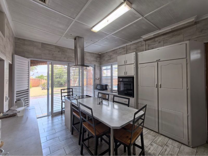 A functional kitchen featuring built-in cabinetry, an integrated oven, extractor fan, and direct access to the outdoor patio area through sliding glass doors.