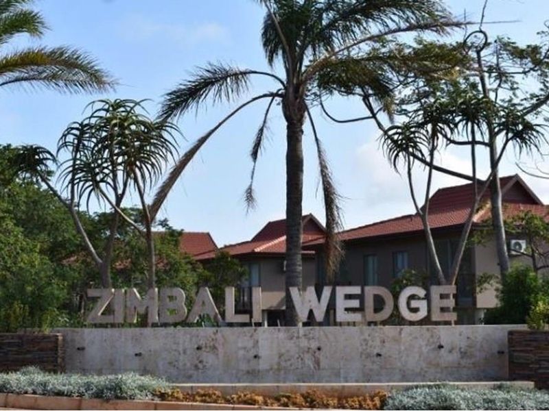Entrance signage and landscaped approach to the Zimbali Wedge residential estate, featuring established palm trees and stone-clad feature wall.