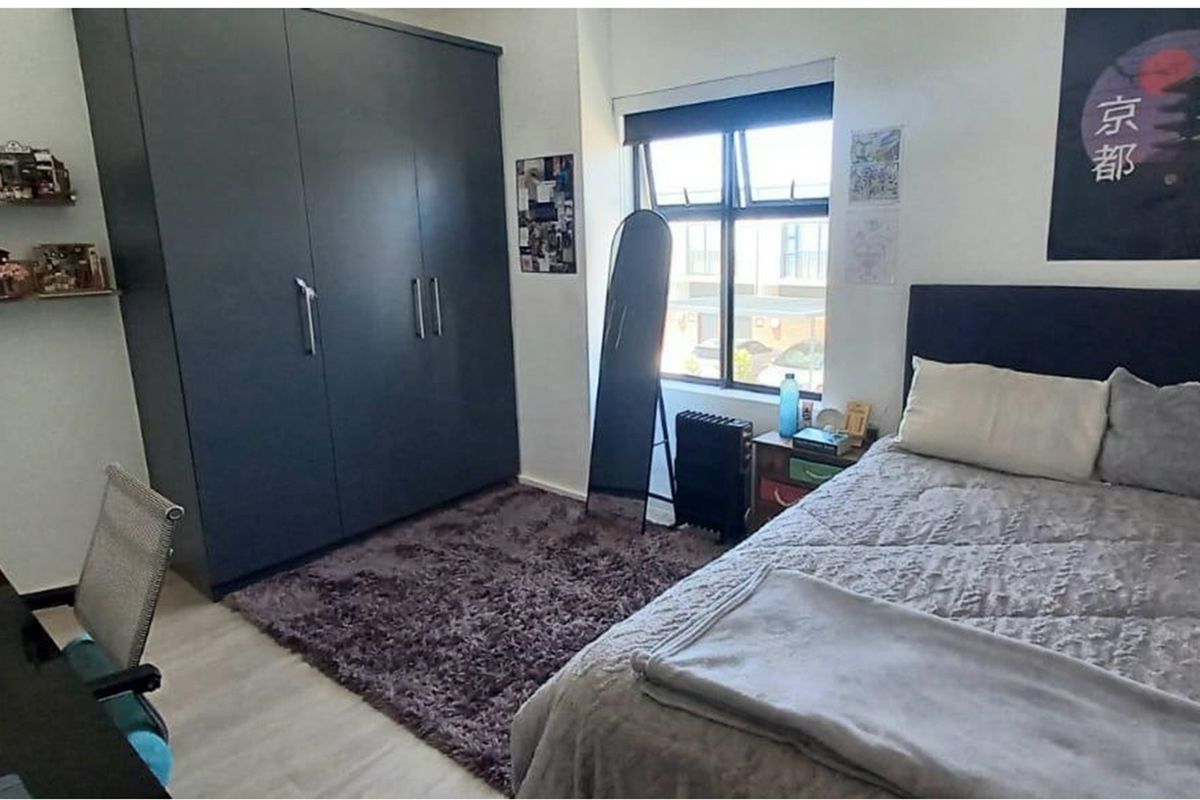 A well-lit bedroom featuring a large built-in wardrobe and modern flooring, offering a comfortable and functional living space.