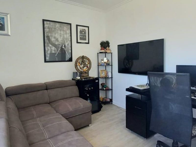A functional living room space featuring light-toned laminate flooring and neutral wall finishes, suitable for a comfortable lounge or home office setup.