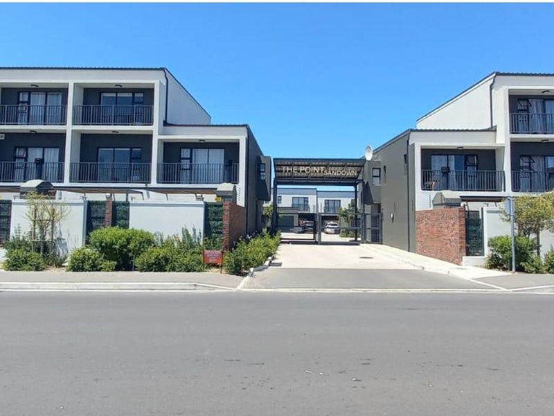 Street view of The Point Sandown townhouse complex entrance, featuring modern multi-story architecture with balconies and a secure gated access point.