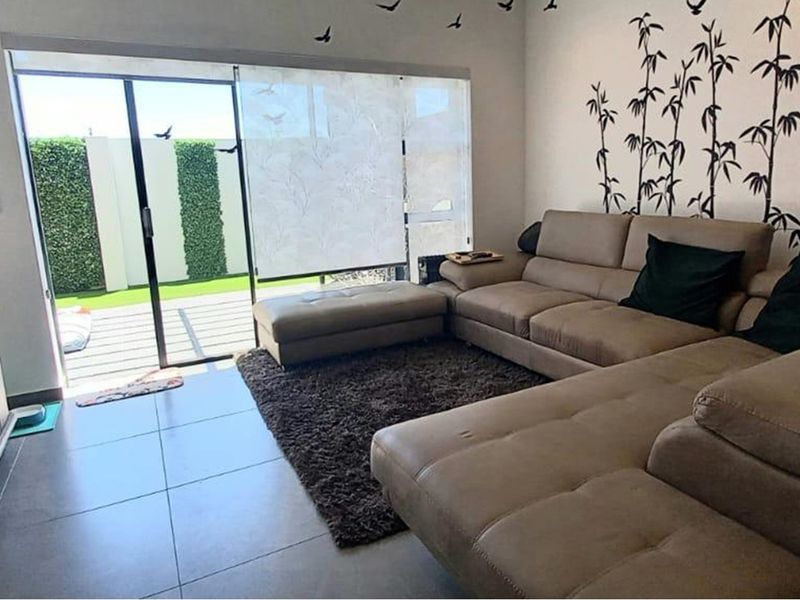 A bright living room featuring large sliding glass doors that open onto a patio area, complemented by neutral tiled flooring.