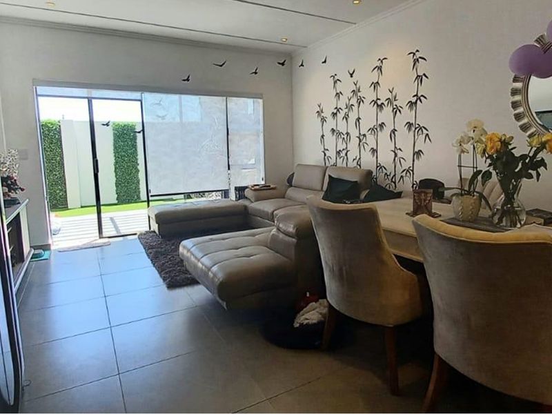 An open-plan living and dining area featuring large format floor tiles and a sliding glass door providing direct access to the outdoor patio.