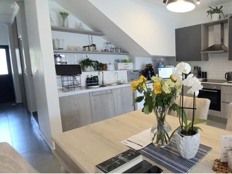 Modern open-plan kitchen featuring sleek cabinetry, integrated appliances, and a tiled backsplash, seamlessly flowing into the dining area under a vaulted ceiling.