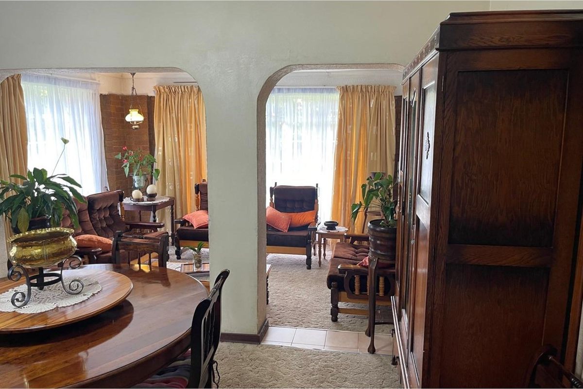 A traditional living area featuring arched doorways, exposed brick accents, and carpeted flooring, providing a classic and connected layout.