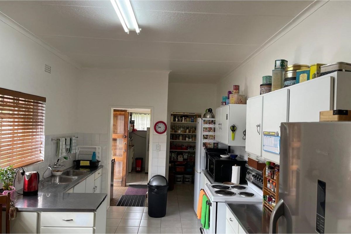 Functional kitchen featuring white cabinetry, stainless steel sink, and an adjacent walk-in pantry area with tiled flooring.
