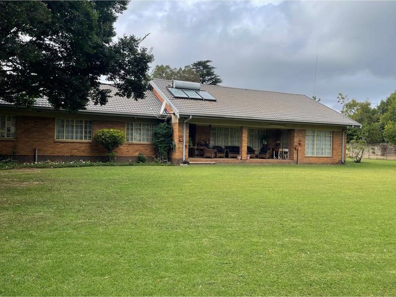 A spacious single-story brick residence featuring a large rear garden, covered patio area, and roof-mounted solar water heating system.