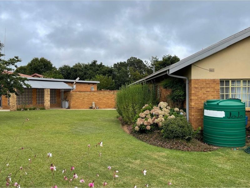 A view of the rear garden featuring a brick exterior, a green water storage tank, and a covered patio area.
