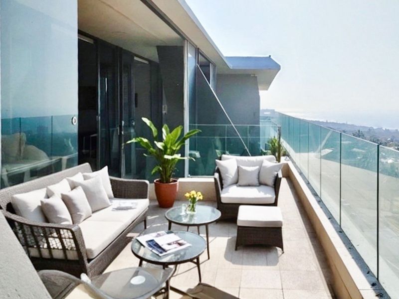 Spacious penthouse balcony featuring a modern glass balustrade, tiled flooring, and seamless access to the interior living area with panoramic views.