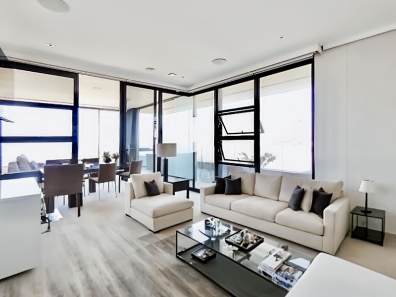 Spacious open-plan living and dining area featuring floor-to-ceiling windows, modern laminate flooring, and seamless access to the balcony.