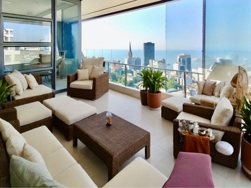 Spacious covered balcony featuring tiled flooring, glass balustrades, and expansive city and ocean views, accessible via large sliding glass doors.
