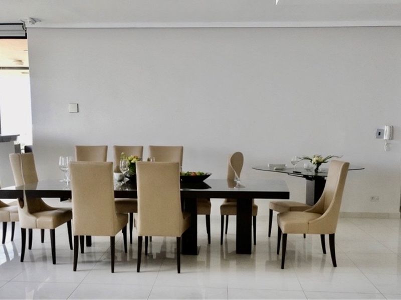 A bright and spacious dining area featuring polished tiled flooring and neutral walls, providing a clean and modern setting for formal meals.