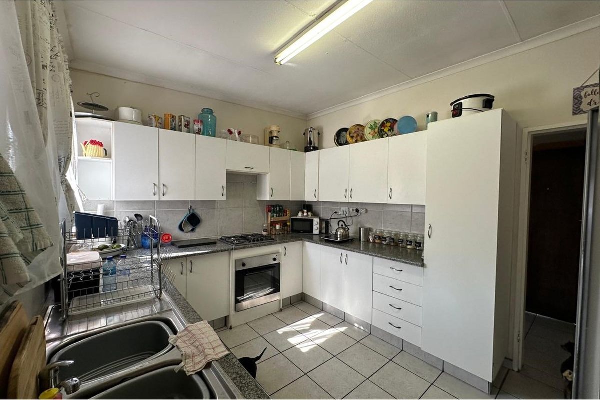 A functional kitchen featuring white cabinetry, granite-look countertops, a built-in oven, gas hob, and tiled flooring.