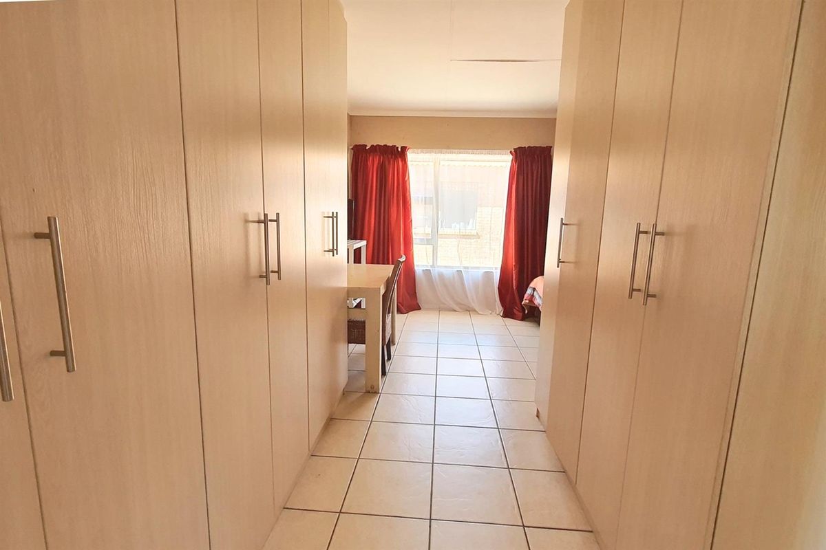 A bedroom featuring extensive built-in cabinetry along both walls, tiled flooring, and a window providing natural light.