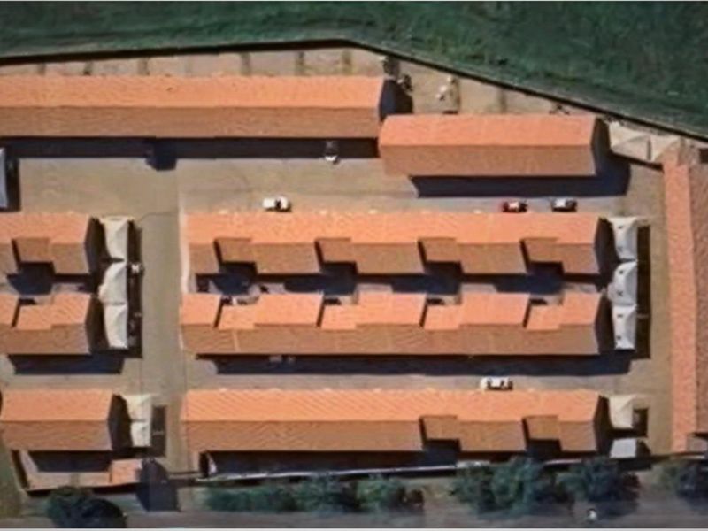 Aerial view of a commercial property complex featuring multiple detached buildings with terracotta-style tiled roofs and paved access ways.