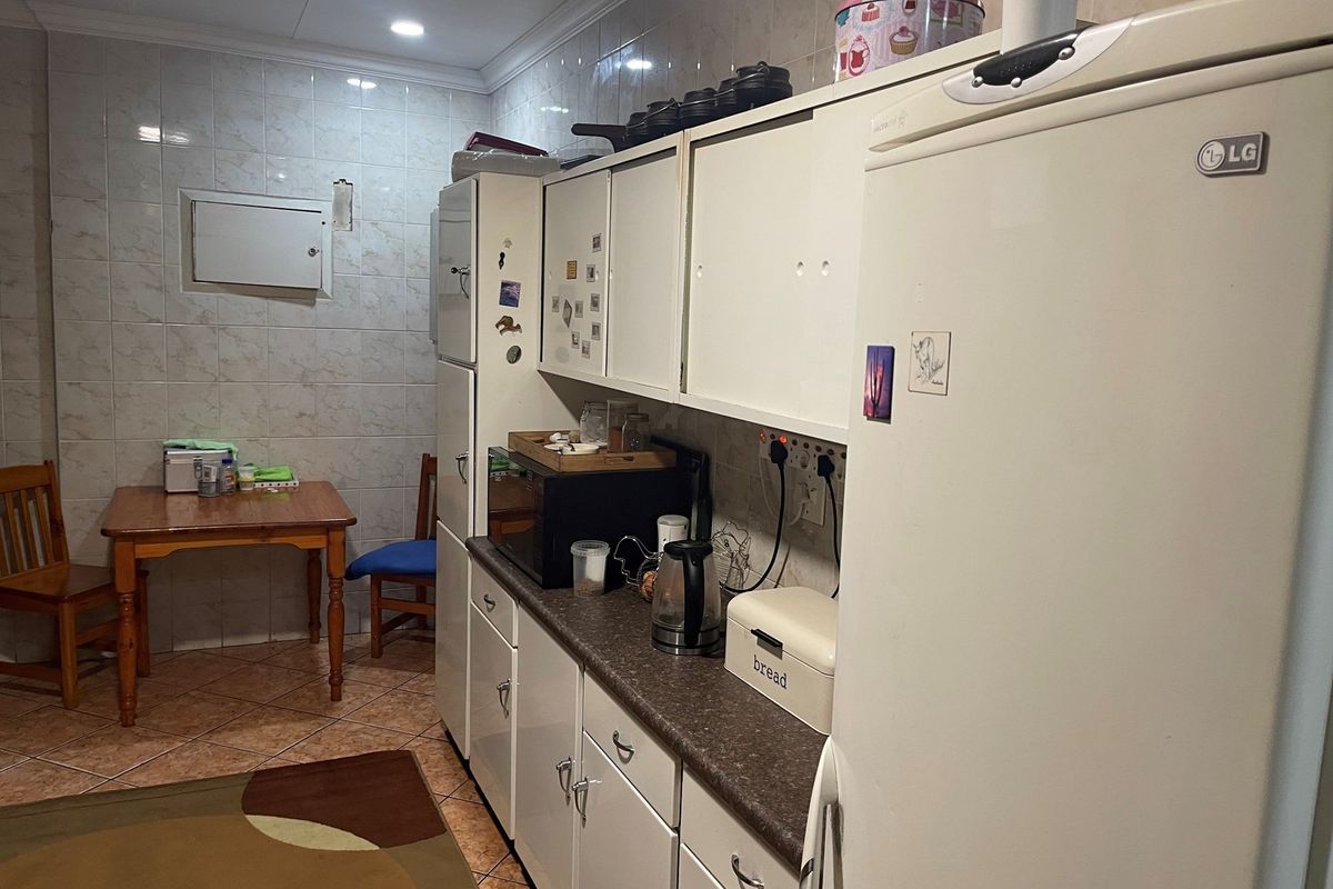 A functional kitchen featuring white cabinetry, laminate countertops, and tiled walls, providing a practical workspace with integrated storage and preparation areas.