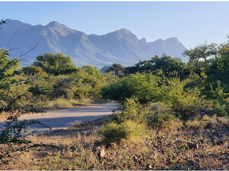 A scenic view of the surrounding natural landscape featuring a paved road leading towards prominent mountain ranges.