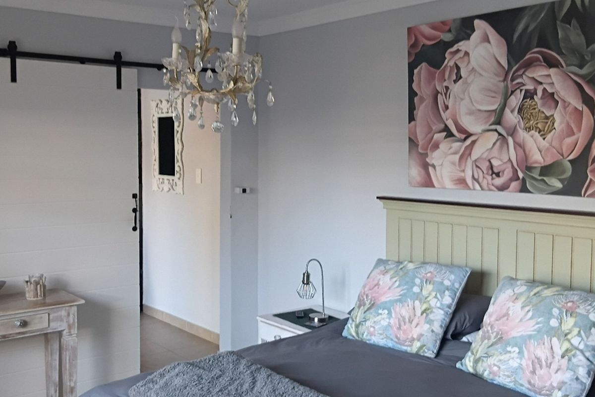 A well-maintained bedroom featuring a sliding barn door, crown molding, and a decorative chandelier.