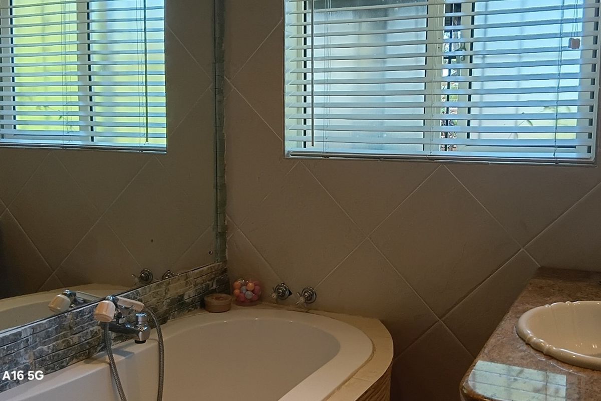 Bathroom featuring a built-in bathtub with chrome fixtures, tiled surround, and a vanity basin with a stone-look countertop.