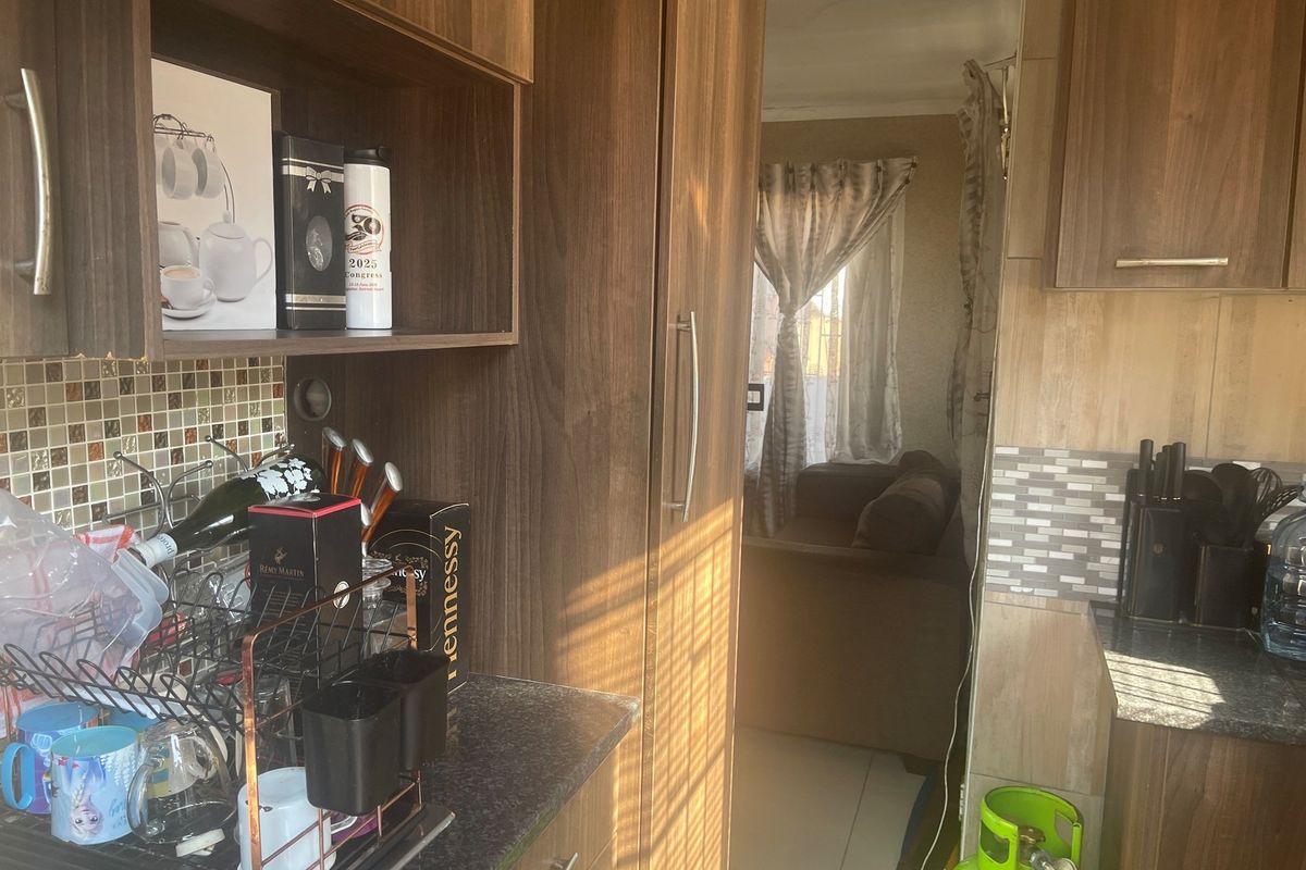 A view from the kitchen area looking through a doorway into the adjacent living space, featuring dark wood cabinetry and mosaic tile backsplashes.