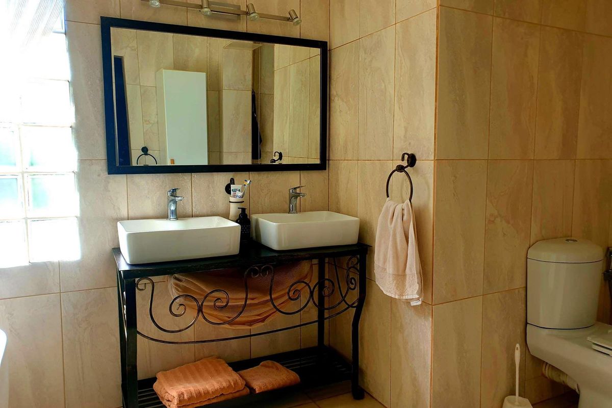 A bathroom featuring a double vanity with vessel sinks, a framed mirror, and full-height wall tiling.