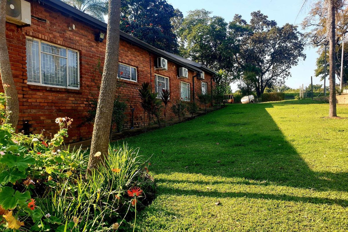 A view of the rear exterior brick facade of the farm building, featuring multiple windows, wall-mounted air conditioning units, and a well-maintained lawn.