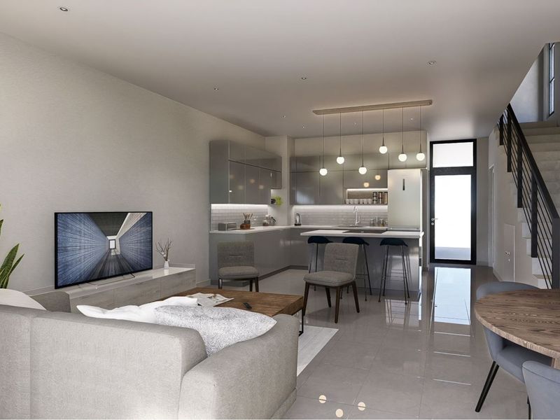 Modern open-plan living area featuring a sleek kitchen with integrated cabinetry, breakfast island, and a staircase leading to the upper level.