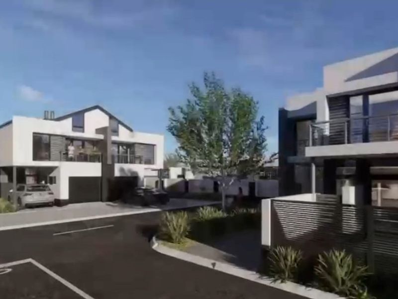 A modern residential apartment complex featuring contemporary architectural design, paved driveways, and landscaped outdoor areas.