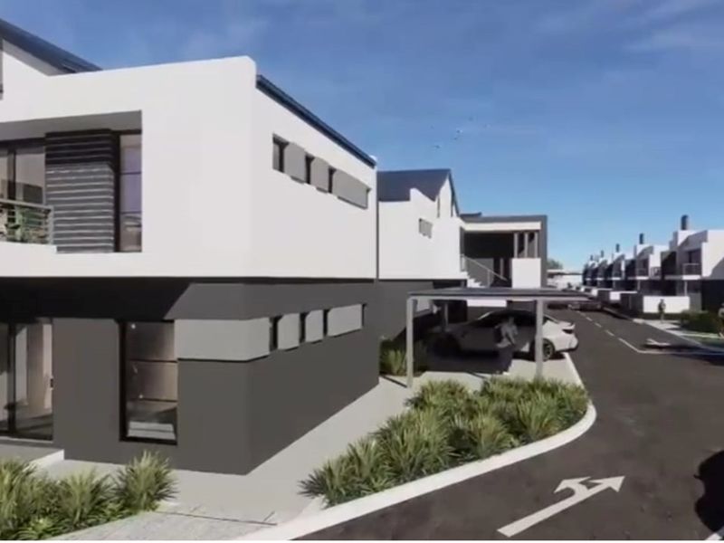 A modern residential complex featuring contemporary architectural design with clean lines, paved driveways, and integrated carport structures.