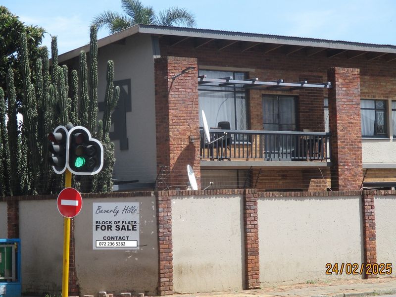 Front view of a brick-faced commercial block of flats featuring a balcony with metal railings and a secure perimeter wall.