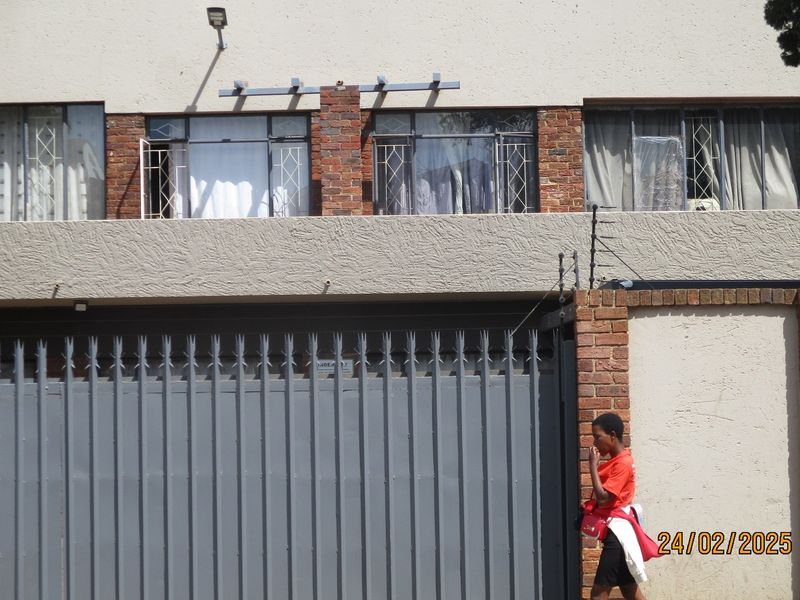 Front elevation of a commercial property featuring a secure metal gate, brick facade, and electric fencing for added security.