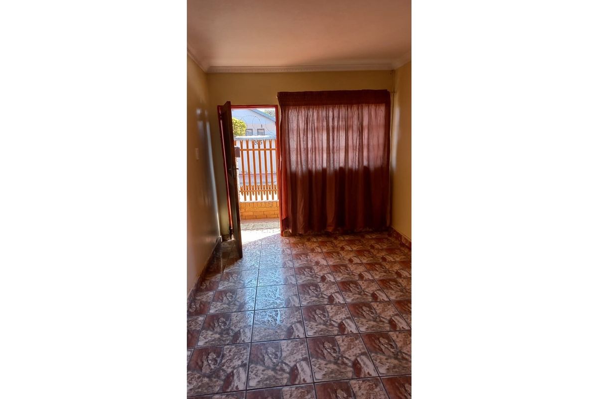 An empty room featuring tiled flooring and direct access to an outdoor area through a doorway.