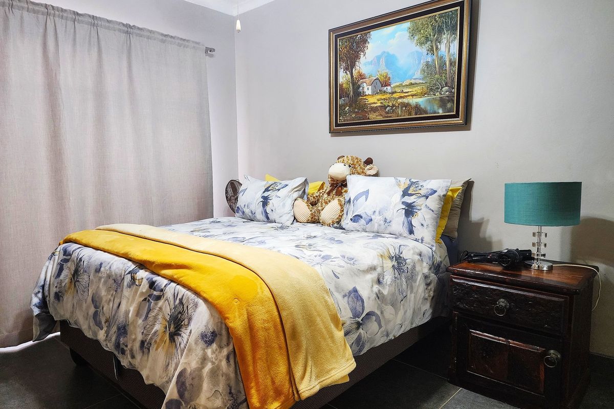 A cozy bedroom featuring tiled flooring, neutral wall finishes, and a window with curtain track installation.