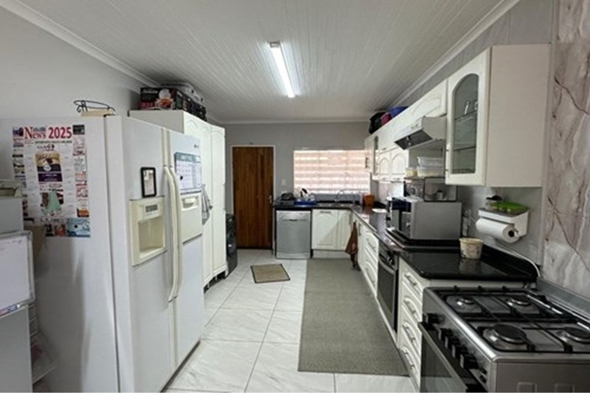 A functional kitchen featuring white cabinetry, dark countertops, a gas stove, and tiled flooring, providing a practical workspace for daily cooking.