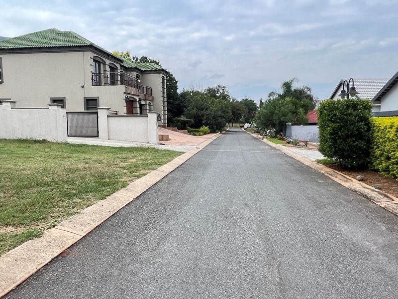 A view of the residential street showing the paved road, concrete curbing, and surrounding property boundaries.