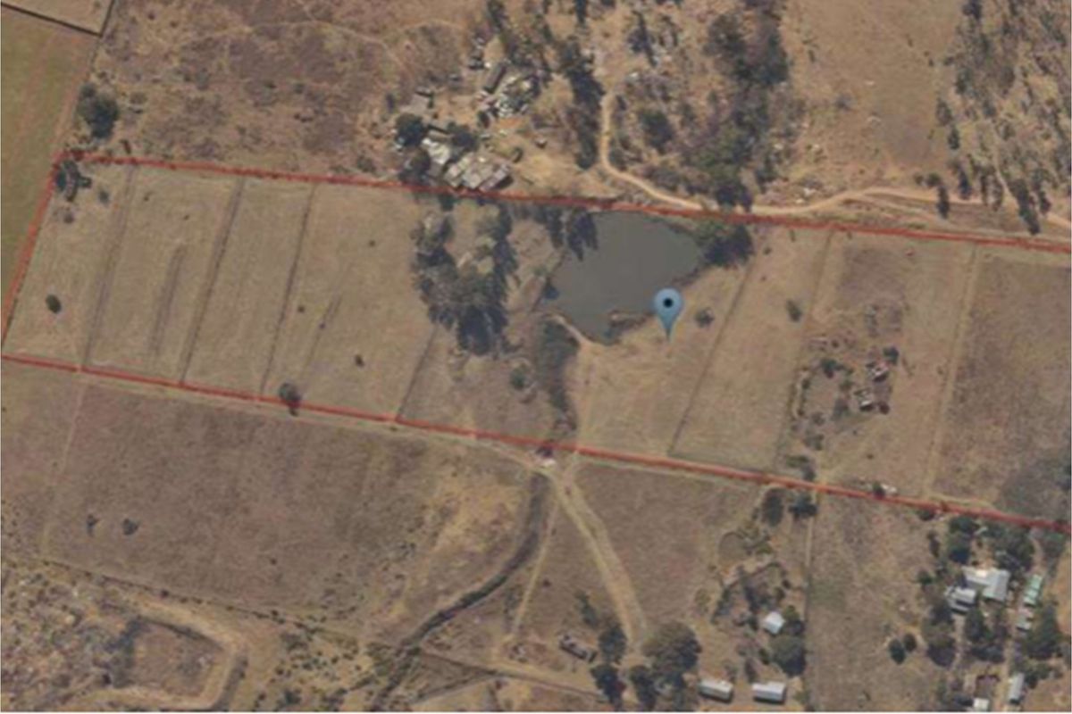 Aerial view of the small holding property showing the land boundaries, open fields, and a small dam on the plot.