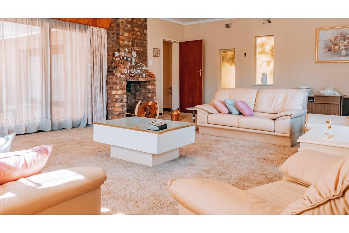 Spacious living room featuring a prominent face-brick fireplace, large sliding glass doors, and neutral carpeting, offering a comfortable and traditional living space.
