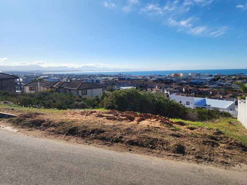Elevated view overlooking the surrounding residential neighborhood, coastal area, and distant mountains from the vacant land plot.