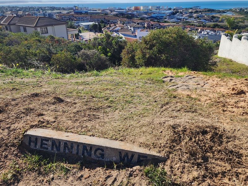 A view of the vacant residential land featuring a concrete street marker, overlooking the surrounding neighborhood and distant coastal landscape.