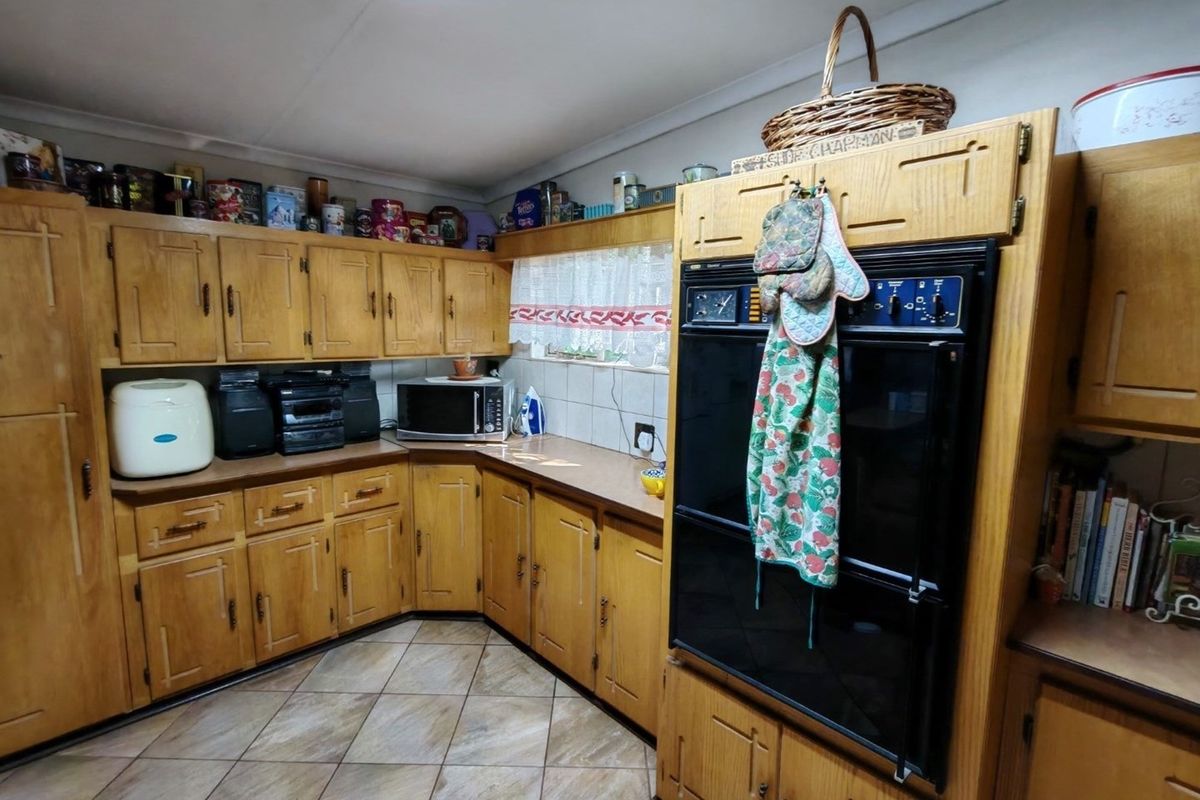 A traditional kitchen featuring extensive wooden cabinetry, a built-in double oven, and tiled flooring, offering a functional layout with ample storage space.