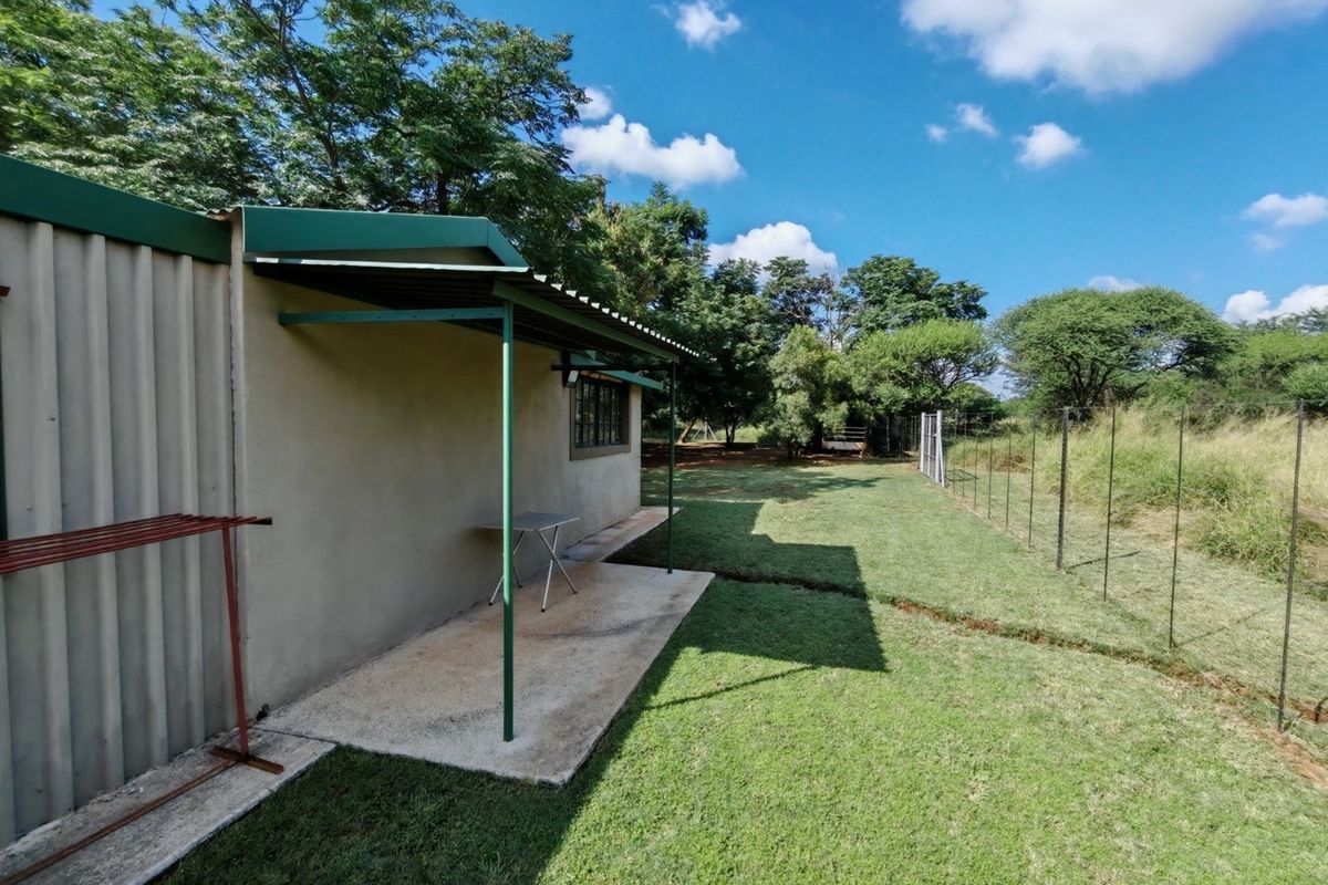 A side view of the property featuring a simple covered patio area, concrete slab flooring, and a fenced garden space.