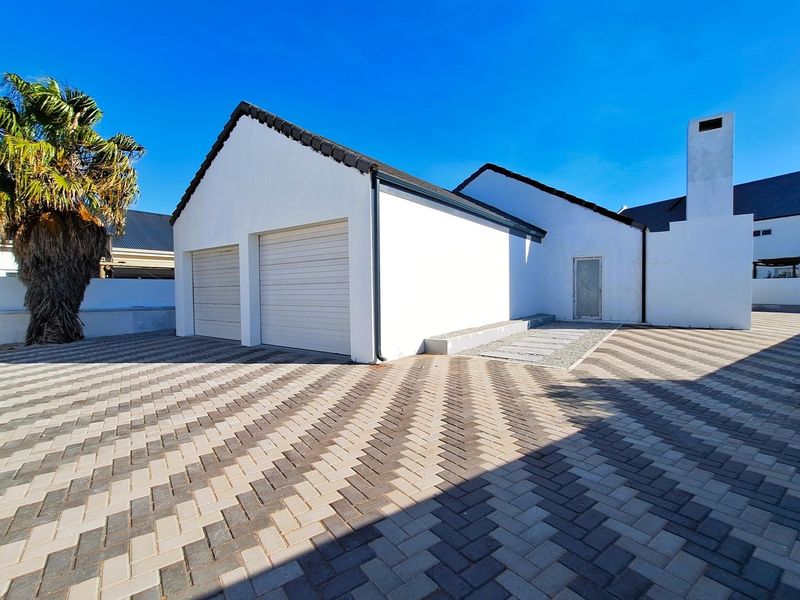 Front exterior view of the property featuring a double garage, paved driveway, and a prominent chimney stack.