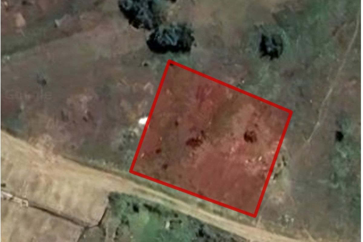 An aerial view of a vacant residential plot of land, showing the boundary lines and surrounding landscape.