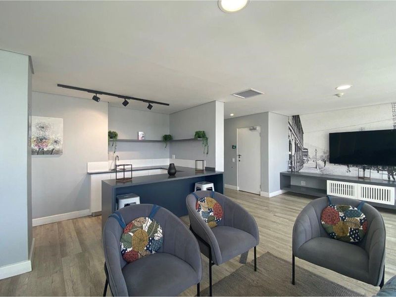 Modern open-plan living area featuring a sleek kitchen with a breakfast bar, integrated cabinetry, and contemporary track lighting, seamlessly flowing into the lounge space.