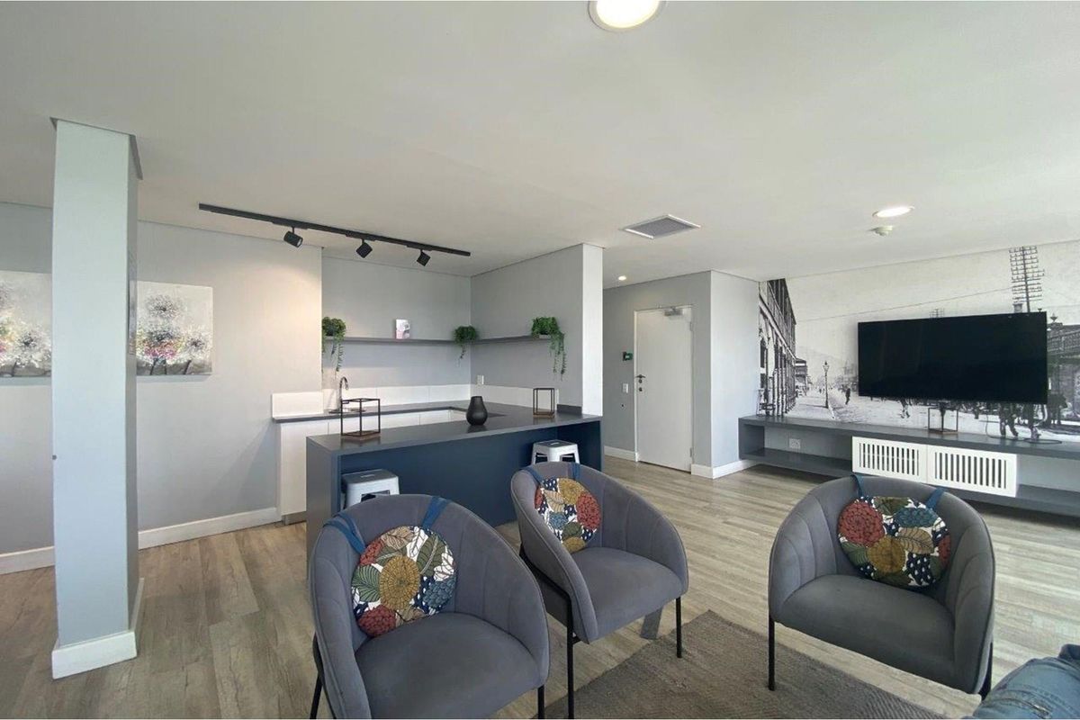 Modern open-plan living area featuring a sleek kitchen with a breakfast bar, integrated cabinetry, and contemporary track lighting, seamlessly flowing into the lounge space.