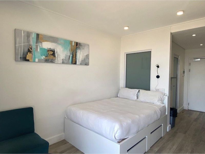 A compact bedroom featuring modern recessed ceiling lighting, light-toned wood-look flooring, and a built-in storage bed base.